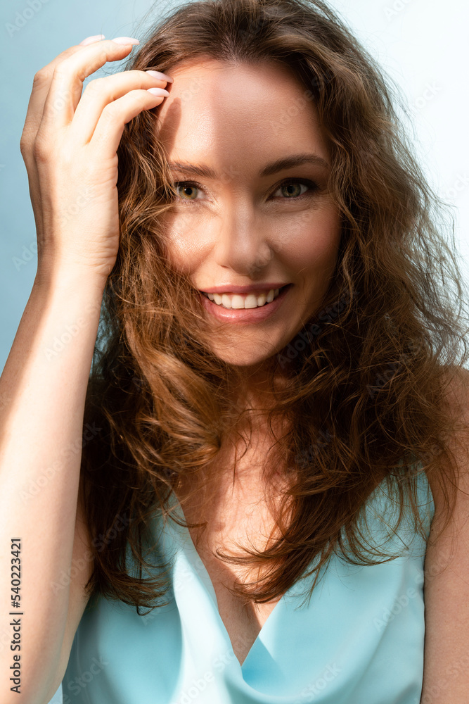 Adult beautiful attractive woman with curly loose hair in the wind in the sunshine moving her hair away from her face Adult beautiful attractive woman with curly loose hair in the wind in the sunshine moving her hair away from her face