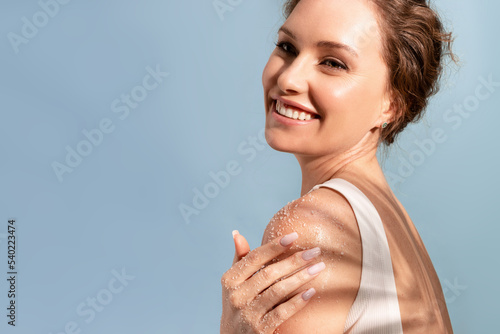 Photos A beautiful tender woman put a natural cosmetic scrub to her shoulder and smiles