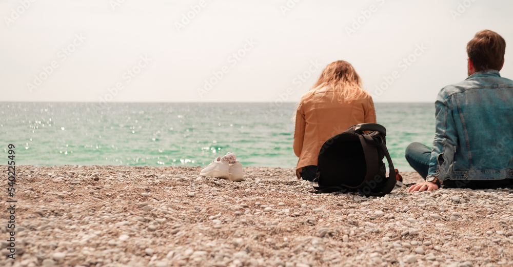 man and woman sitting barefoot on sea shore beach