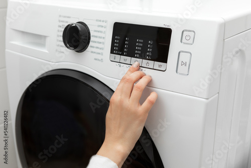 Close-up of a hand selecting a program with a finger while pressing on a washing machine