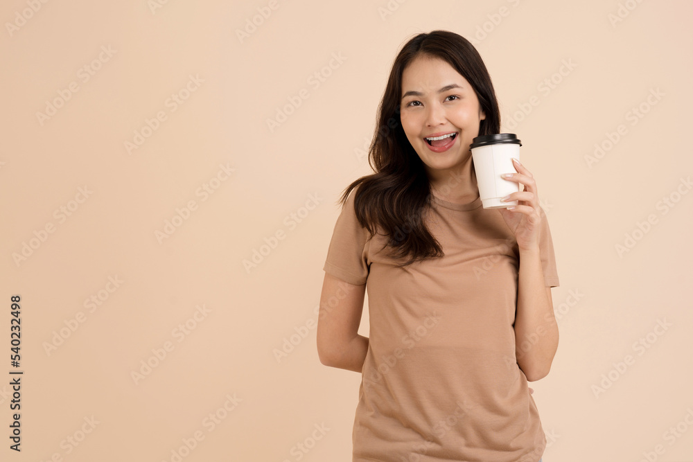 Happy young woman holding coffee cup standing in the studio Happy young woman holding coffee cup standing in the studio