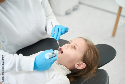 Experienced pedodontist giving local anesthesia to preteen child