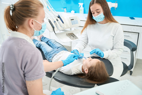 Concentrated pediatric dentist administering anesthesia to patient