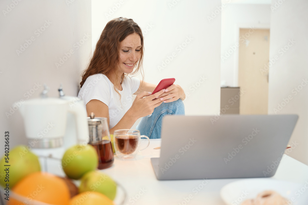 Woman is using smartphone during break from work with laptop Woman is using smartphone during break from work with laptop