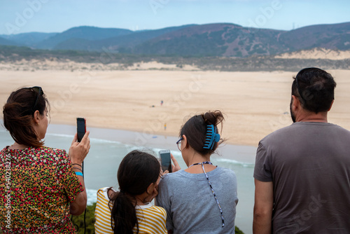 Portugal, August 2022: Family on vacation taking pictures of the beach in Algarve, Portugal