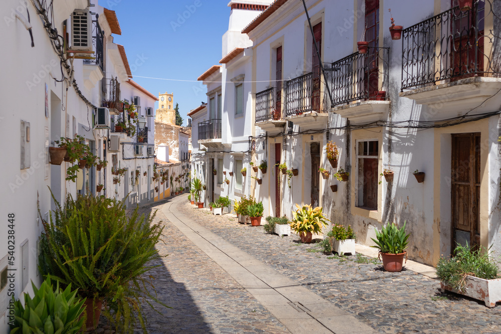 Portugal, August 2022: Traditional cobbled street with white houses and plants on the street, Castelo de Moura street, Algarve, Portugal
