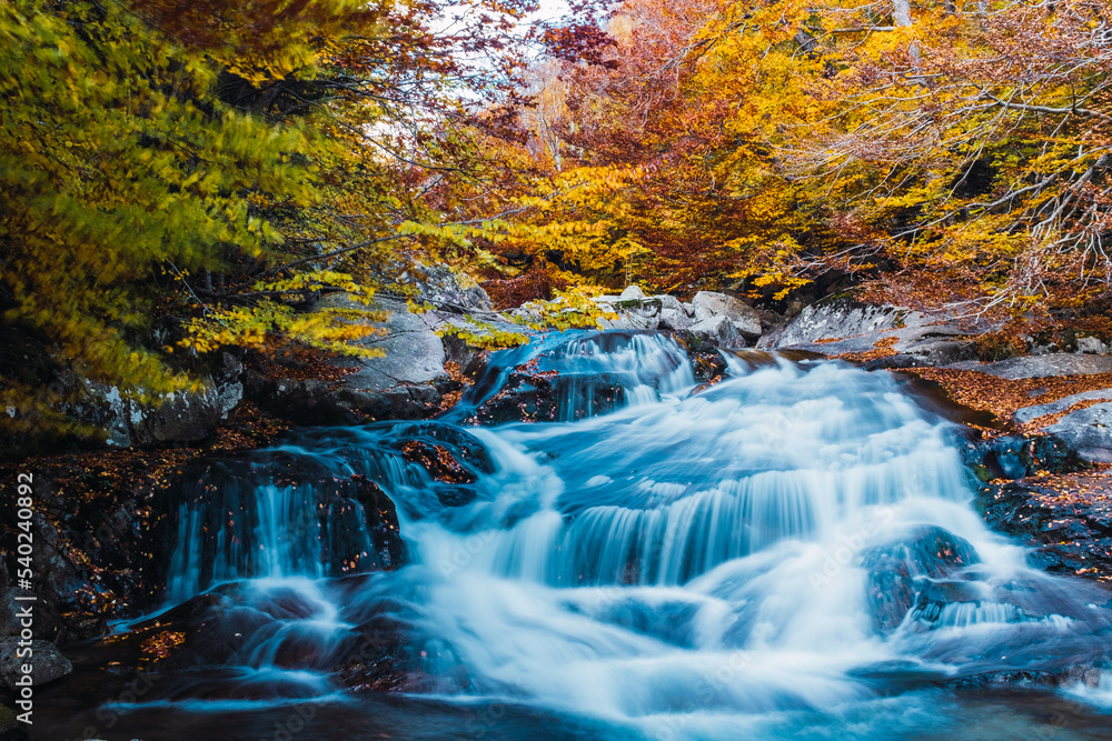 Long exposure of a waterfall with fall colors in the background. Long exposure of a waterfall with fall colors in the background.