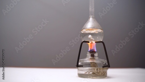 Bulb with boiling liquid on burner flame. Flask heated on burner in laboratory photo