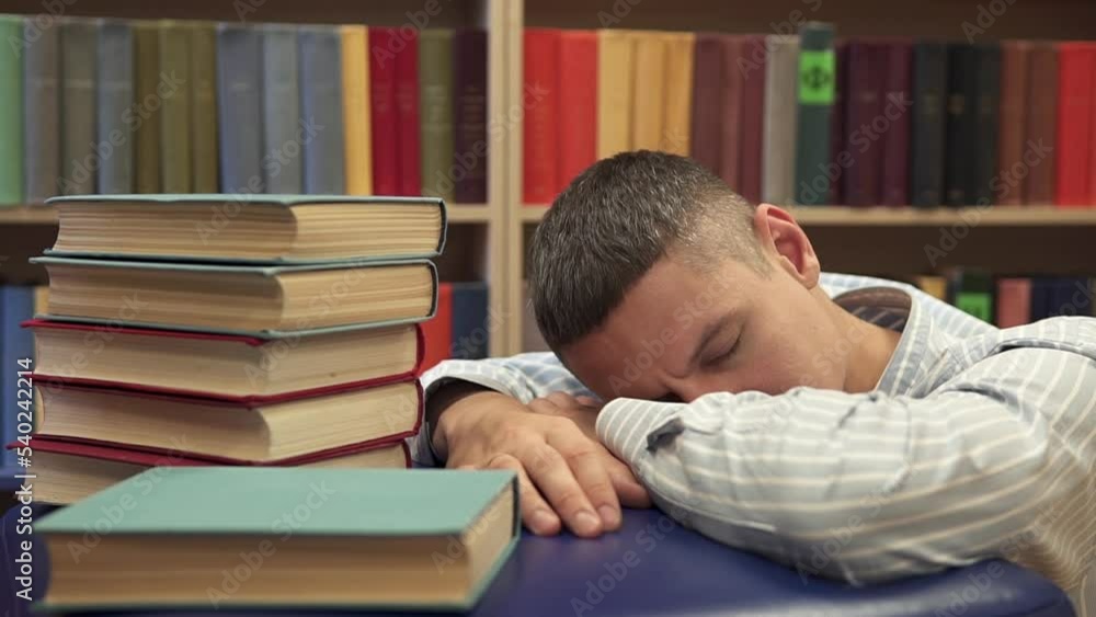 The student fell asleep between the rows of bookshelves preparing for the exam. University Library. The student fell asleep between the rows of bookshelves preparing for the exam. University Library.