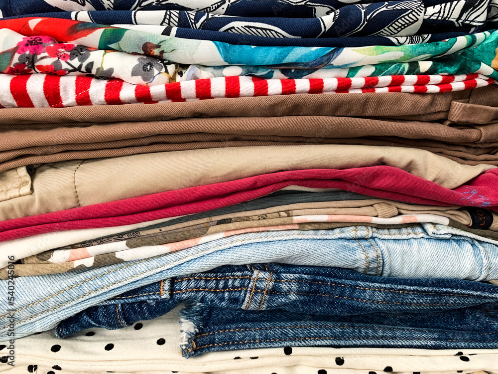 Pile of clothes on a basket. A pile of ironed colorful female clothes on a white wicker basket ready to be organised in wardrobe Pile of clothes on a basket. A pile of ironed colorful female clothes on a white wicker basket ready to be organised in wardrobe