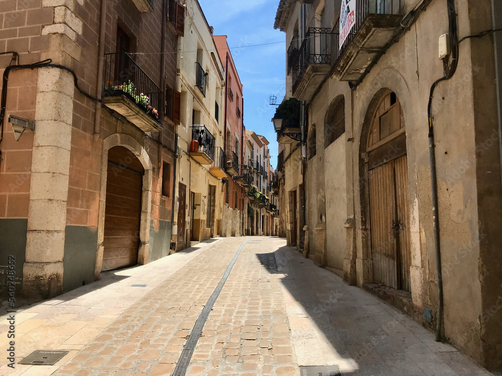 Fototapeta premium Montblanc, Spain, June 2019 - A large brick building with a clock on the side of the street