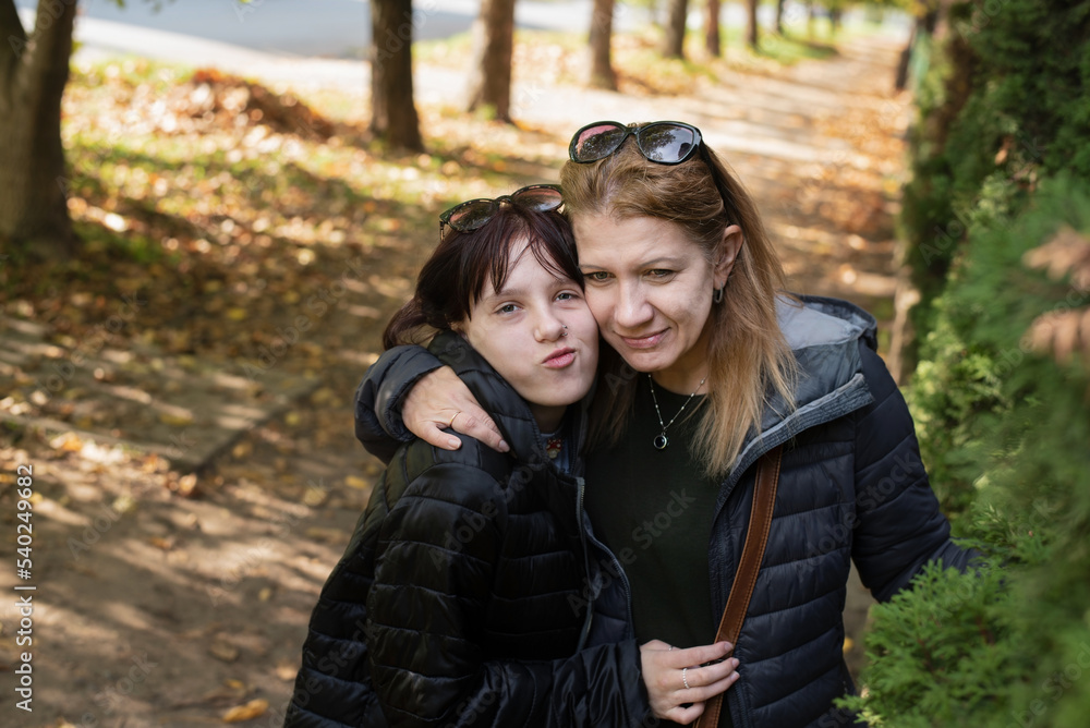 Fototapeta premium A woman gently hugs her teenage daughter and they have fun together, fooling around. A mother tells her daughter how much she loves her. Friendly relations between mother and daughter