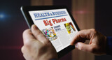 Big Pharma and pharmaceutical business newspaper on mobile tablet screen