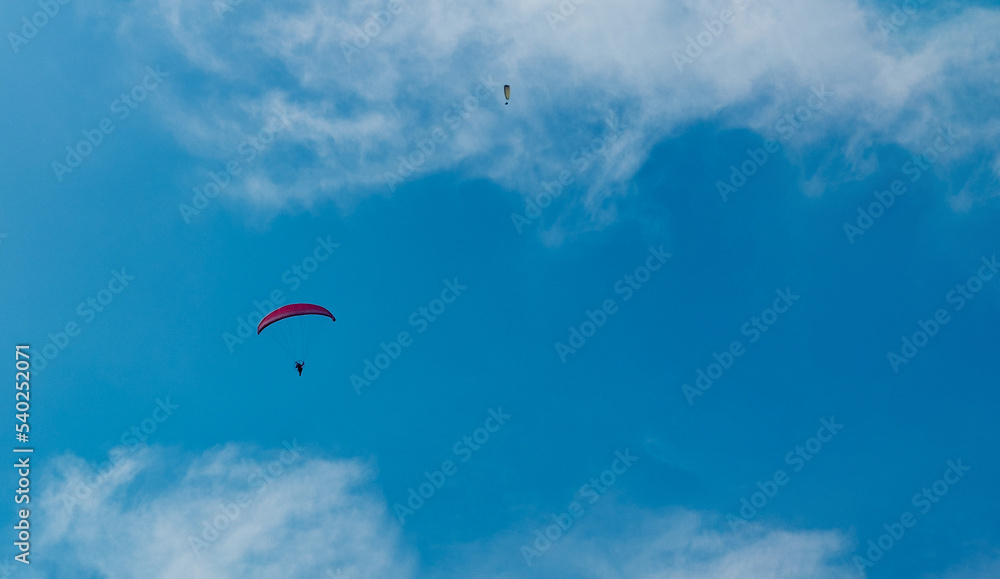paragliding pilot flying high in the blue sky with clouds paragliding pilot flying high in the blue sky with clouds