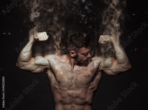 Muscle shirtless bodybuilder flexing his biceps, disintegrating into particles, dramatic image