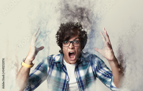 Screaming tortured furious man dispersing into particles photo