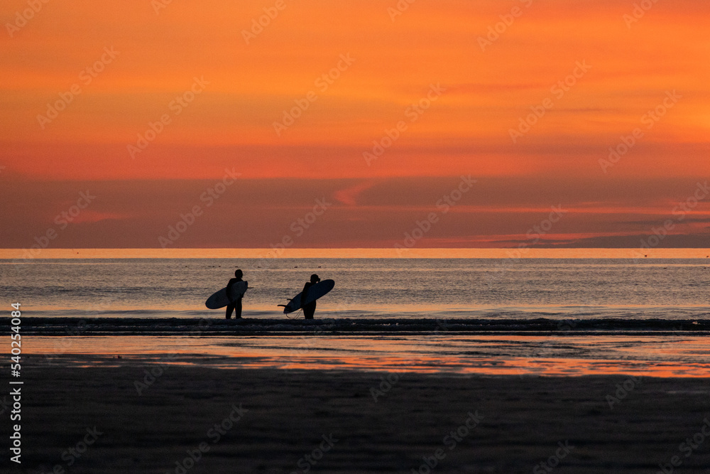 surfers leaving ocean at sunset