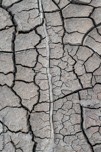The ground has cracks in the photo from above for a background or graphic design with the concept of drought and death.
