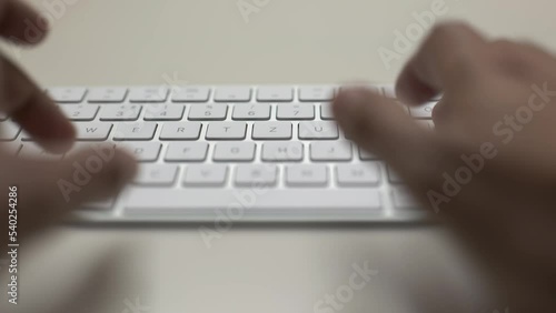 Typing on flat white computer keyboard, close up