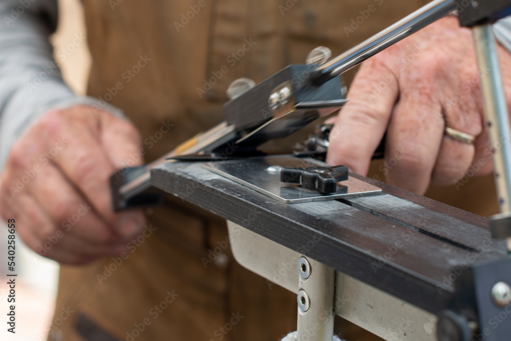 Fotka „A man using a fixed angle knife sharpener kitchen tools at a farmer's market to sharpen