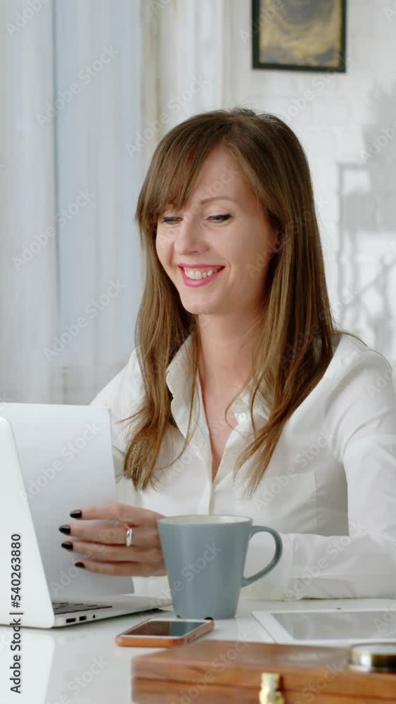 Young business woman working at desk with laptop computer in home office. Getting document looking relieved. Young business woman working at desk with laptop computer in home office. Getting document looking relieved.
