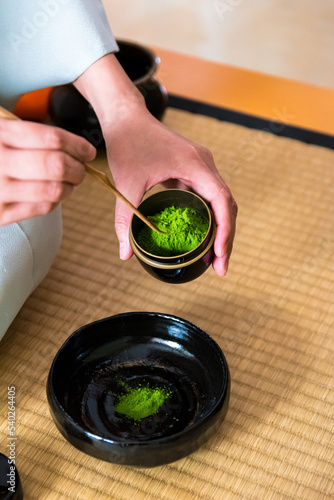 Japanese woman, tea master, Sen Rikyu, hands placing matcha powder into chawan tea bowl during a Japanese traditional tea ceremony