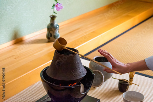 Japanese woman, tea master, Sen Rikyu, hands performs ritual to lay down Hishaku bamboo ladle on top of chagama kettle during a Japanese traditional tea ceremony