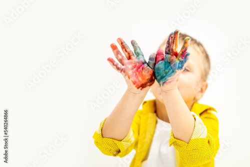 a little boy child with painted hands stained in paint in yellow clothes on a white isolated background was drawing  hands in focus