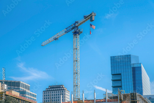Austin, Texas- Tall tower crane with hanging US flags above the under construction building