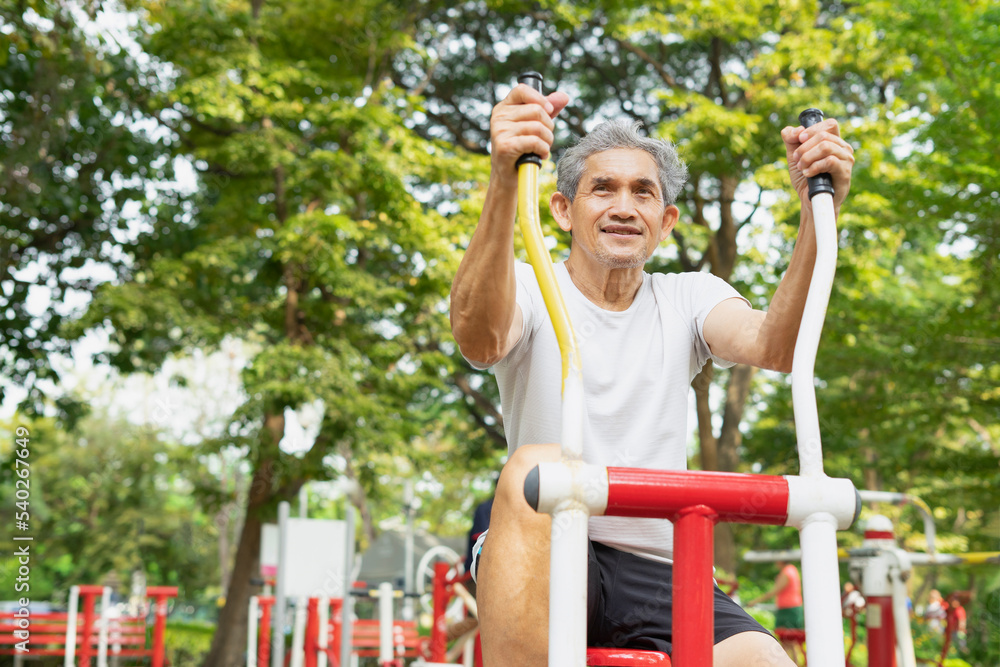 Obraz premium A healthy senior man with grey hair doing exercise on outdoor fitness equipment in the city park, concept for elderly people lifestyle, health, health care ,wellness