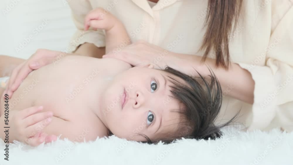 Little girl lay on the cloth for her mother to sprinkle baby powder after taking a shower. Little girl lay on the cloth for her mother to sprinkle baby powder after taking a shower.