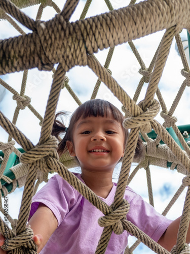 Smiling child in a rope tunnel at the playground.
