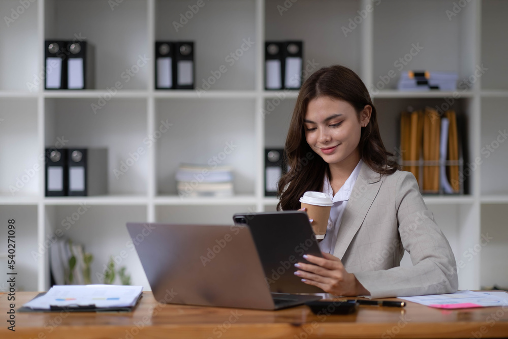 Photo of cheerful young woman working using computer laptop concentrated and smiling at office Photo of cheerful young woman working using computer laptop concentrated and smiling at office