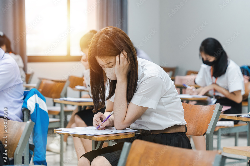 Obraz premium College students writing on final examination papers in the classroom concentrately