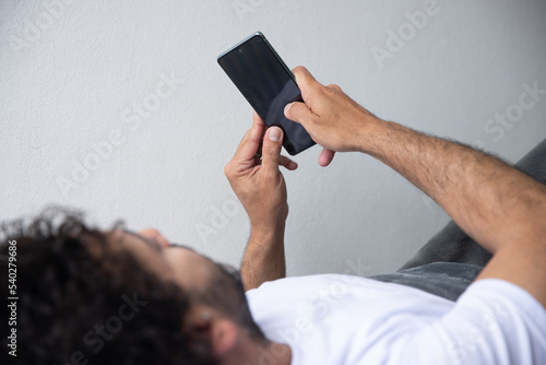 man lying on his bed looking at his phone