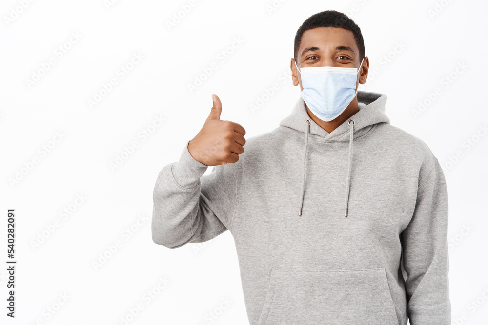 Covid awareness, healthcare concept. Image of happy african american man in medical mask, shows thumbs up Covid awareness, healthcare concept. Image of happy african american man in medical mask, shows thumbs up