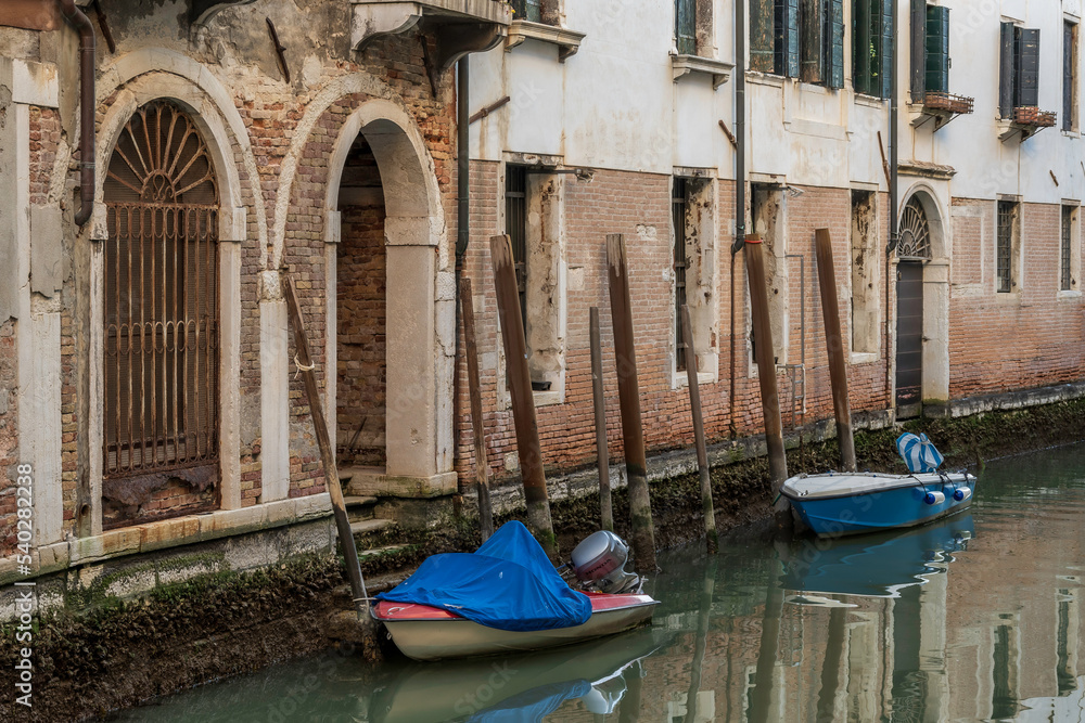 Small boats parked in a typical canal in the heart of Venice, Italy