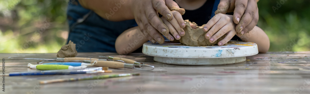Close up pottery teacher hands teaching kid to creat model clay in pottery workshop, art and craft
Kid Artist concept Close up pottery teacher hands teaching kid to creat model clay in pottery workshop, art and craft
Kid Artist concept