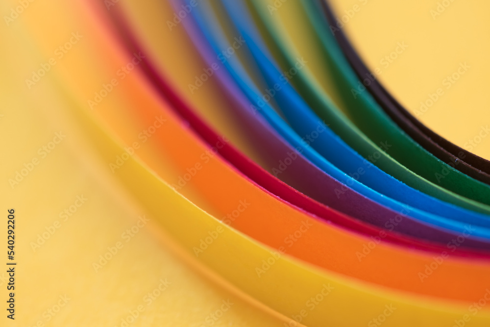 Colorful paper strips on yellow hammer paper, abstract background with vibrant colors, shallow depth of field, blurred lines Colorful paper strips on yellow hammer paper, abstract background with vibrant colors, shallow depth of field, blurred lines
