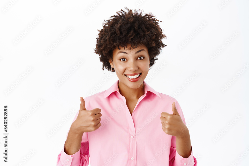Image of smiling corporate woman, businesswoman shows thumbs up, yes sign, approve smth, recommends company or product, white background Image of smiling corporate woman, businesswoman shows thumbs up, yes sign, approve smth, recommends company or product, white background