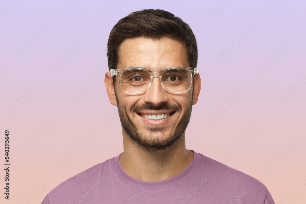 Smiling modern nice guy in t-shirt and trendy trasparent eyeglasses isolated on purple background Smiling modern nice guy in t-shirt and trendy trasparent eyeglasses isolated on purple background