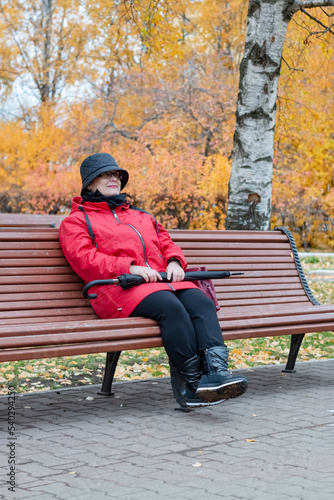 An elderly woman is sitting on a bench.