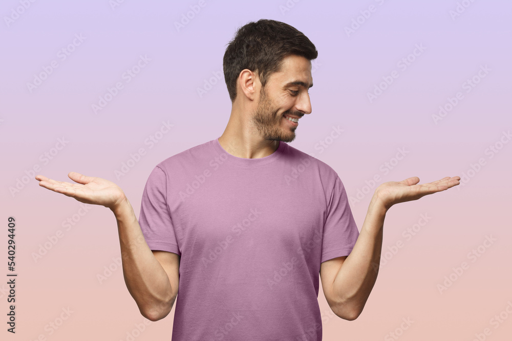 Young handsome male choosing between two different options, holding 2 hands, isolated on purple Young handsome male choosing between two different options, holding 2 hands, isolated on purple