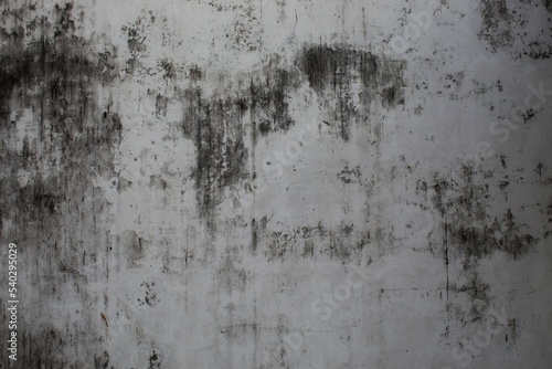 A weathered concrete wall with cracks and peeling paint, showing signs of age and decay.