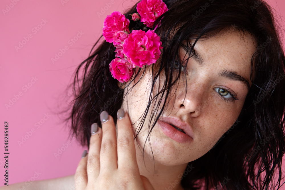 Naklejka premium a beauty brunette woman portrait,a pink flower in the hand near face