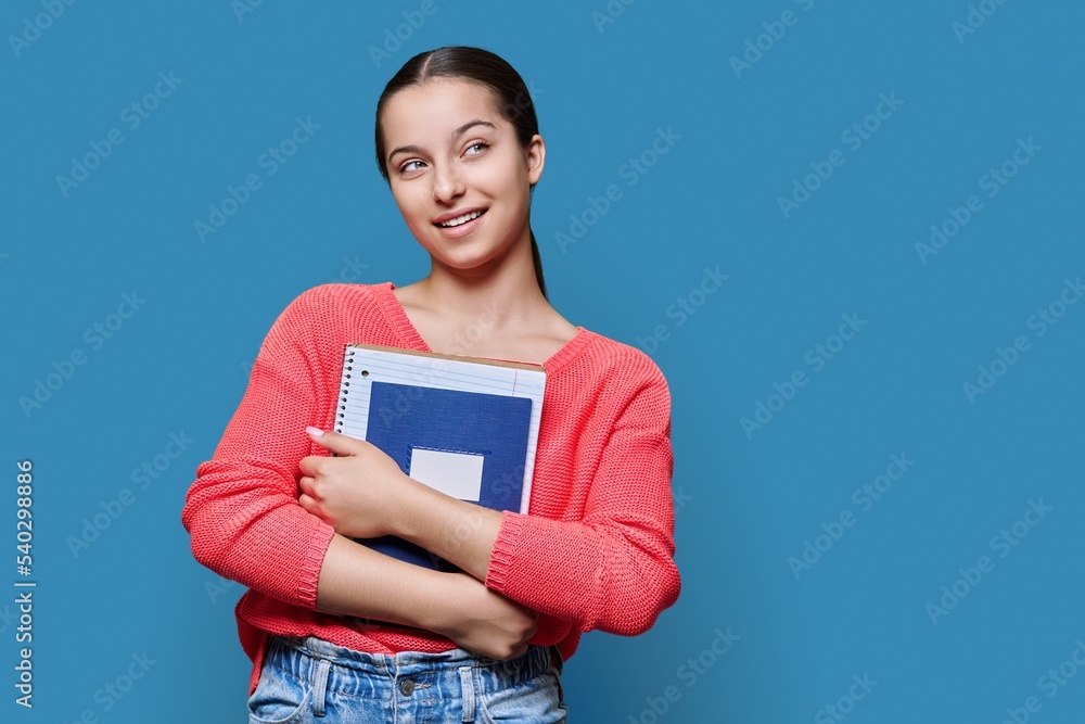 Obraz premium Portrait of teenage high school student on blue color studio background