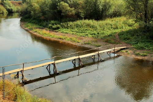Flimsy makeshift wooden bridge across a small river