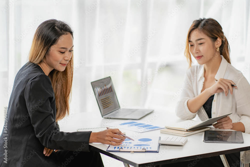 Fototapeta premium Two Asian businessmen or accountants brainstorm financial charts. Two Asian female financial advisors or analysts work. Discuss financial reports together.