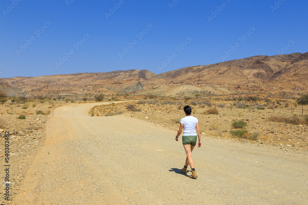 Woman on a gravel road , Namibian landscape. Namibia.