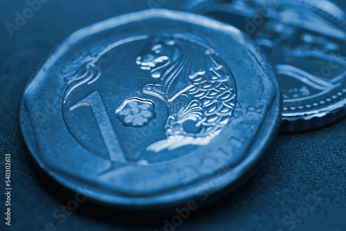 1 Singapore dollar. Fragment of textured coin. Blue tinted background or wallpaper about economy or finance. Coins and money change of Singapore. News about banks and currency. Macro